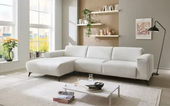 Großes Ecksofa im hellen natur durchleuchteten Raum mit kleinem Couchtisch.